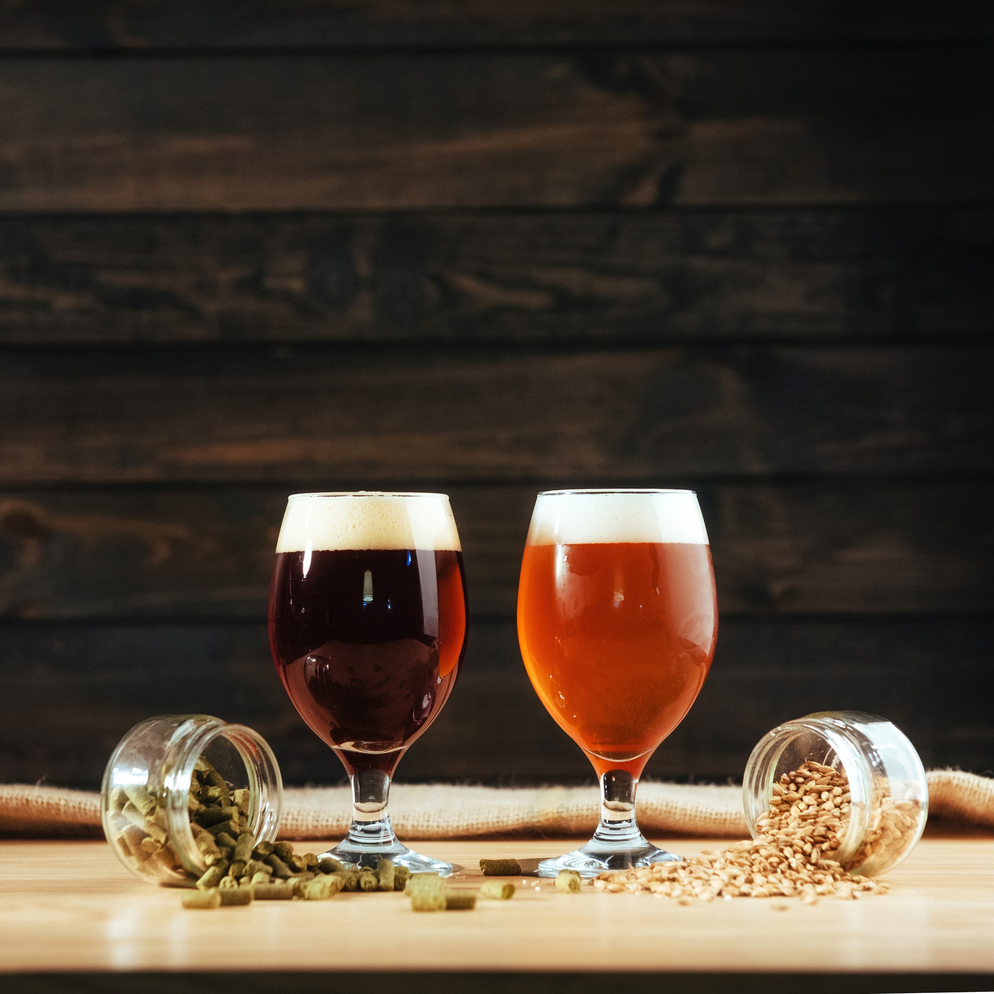 Two glasses of beer on a wooden table grains